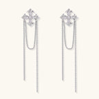 White gold plated baroque cross stud earrings with long cascading zirconia chains on cream background
