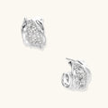 Close-up of sculptural hoop earrings with lattice center band and smooth twisted edges in white gold-plated brass with zirconia