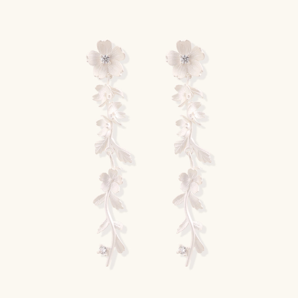 Long sterling silver drop earrings with delicate floral vine design and crystal accents on white background