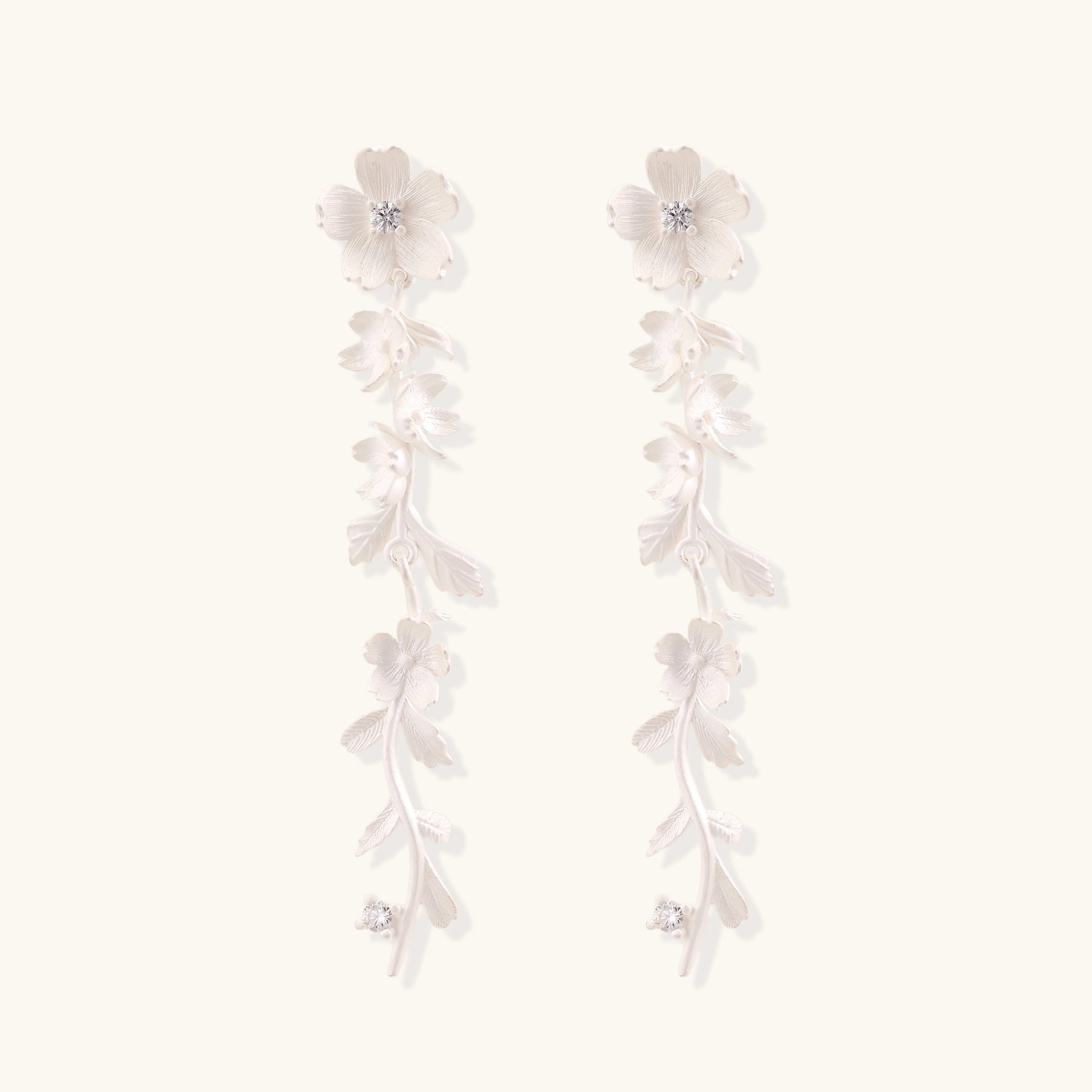 Long sterling silver drop earrings with delicate floral vine design and crystal accents on white background