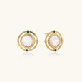 Circular gold stud earrings with iridescent mother-of-pearl center and green zirconia accents on cream background.