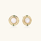 Circular gold stud earrings with iridescent mother-of-pearl center and green zirconia accents on cream background.
