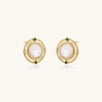 Circular gold stud earrings with iridescent mother-of-pearl center and green zirconia accents on cream background.
