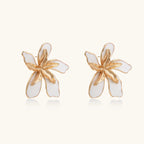 White enamel tropical flower earrings with sculptural gold-plated center and organic petal design on cream background