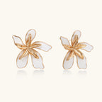White enamel tropical flower earrings with sculptural gold-plated center and organic petal design on cream background
