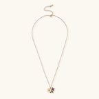 Gold-plated necklace with pink and purple enamel flower pendant featuring crystal accents on cream background