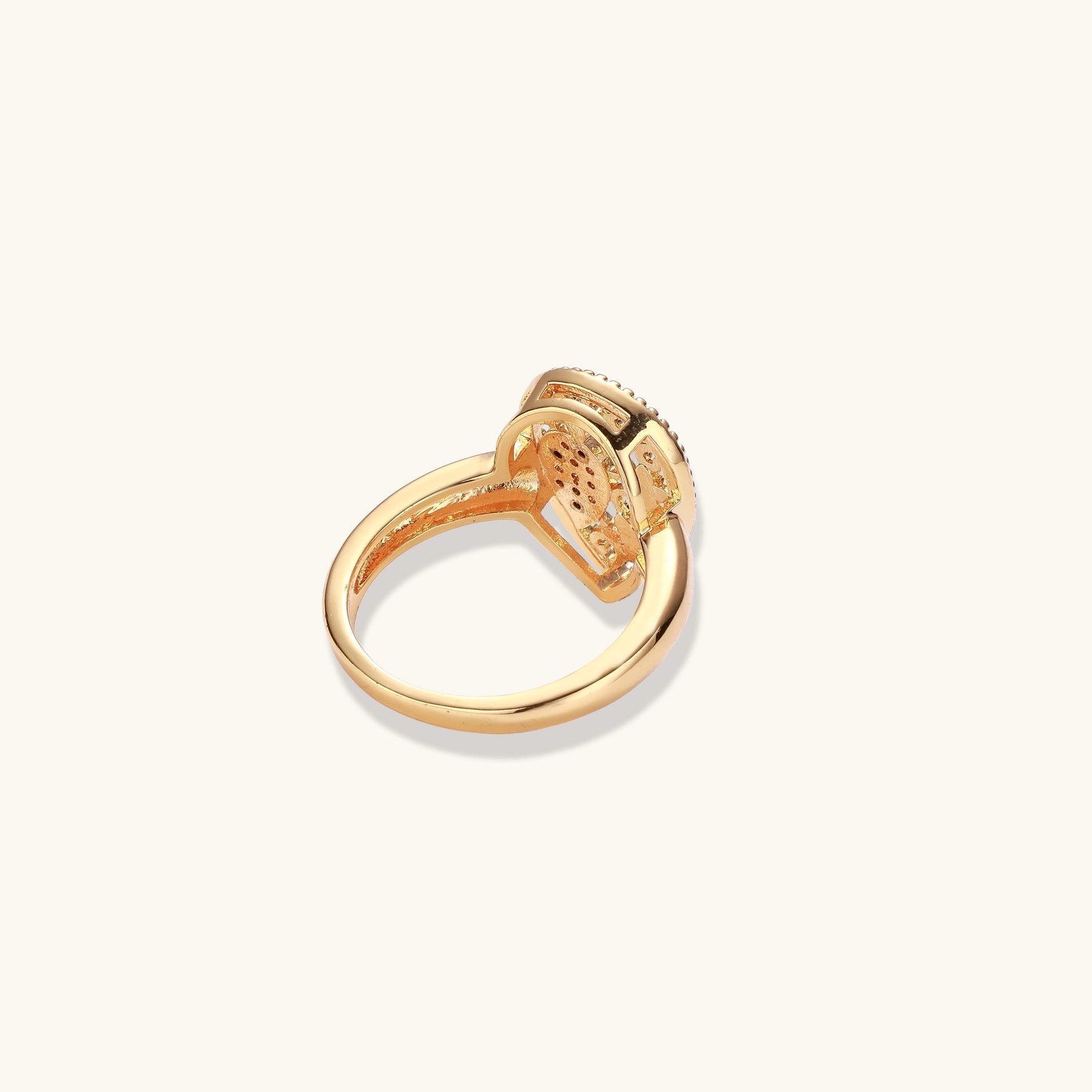 Teardrop-shaped gold-plated ring with turquoise enamel flowers and crystal pavé detail on cream background