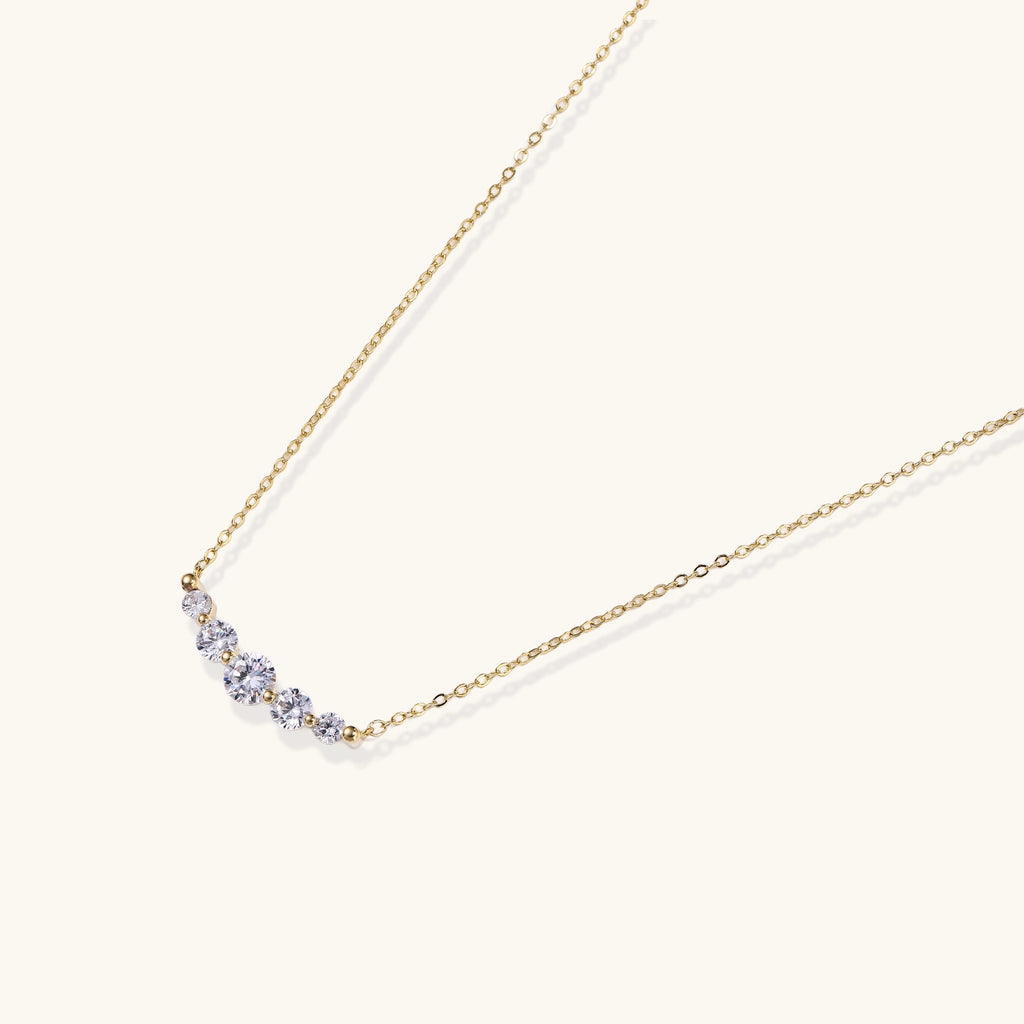 Delicate 14K gold-plated necklace with five graduated zirconia stones arranged in a curved arc on fine chain