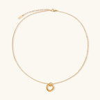 Delicate gold-plated necklace with three interlocking circle rings forming a minimalist knot pendant on cream background