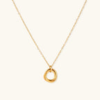 Delicate gold-plated necklace with three interlocking circle rings forming a minimalist knot pendant on cream background
