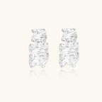 White gold plated sculptural hoop earrings with organic wavy edges and reflective metallic finish on cream background