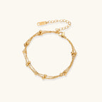 Three-strand gold-plated bracelet with clustered ball beads and adjustable clasp on cream background
