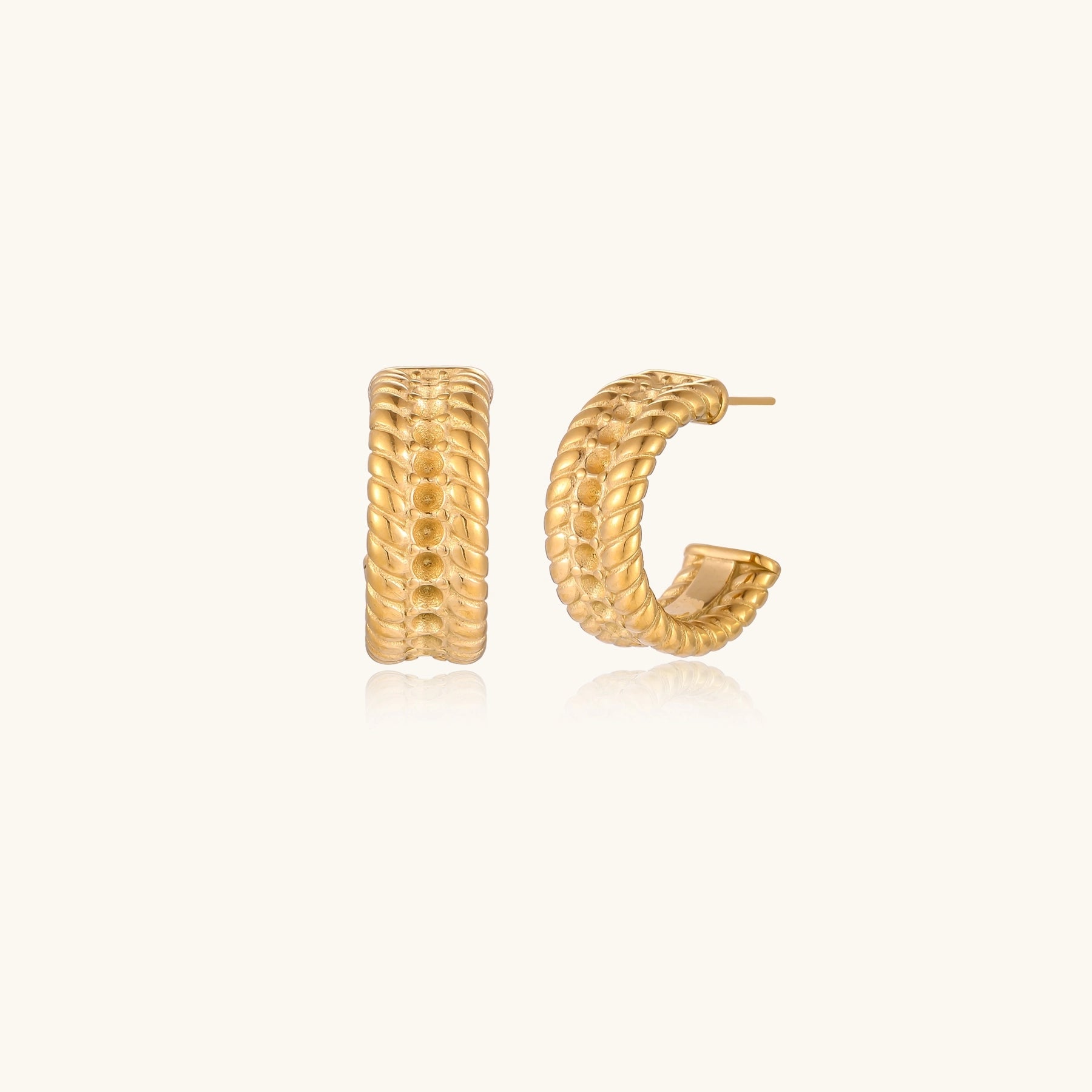 Textured gold huggie hoop earrings with raised ribbed rows creating dimensional sculptural design on cream background