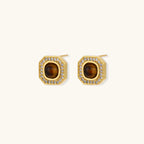 Gold-plated octagonal stud earrings with brown tiger's eye centers and cubic zirconia border on cream background.
