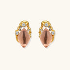 Gold-plated baroque stud earrings with coral-pink liuli stones and cubic zirconia crystals on white background.