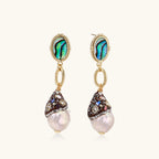 Gold drop earrings with iridescent abalone studs, rope links, jeweled caps and white baroque pearls on cream background