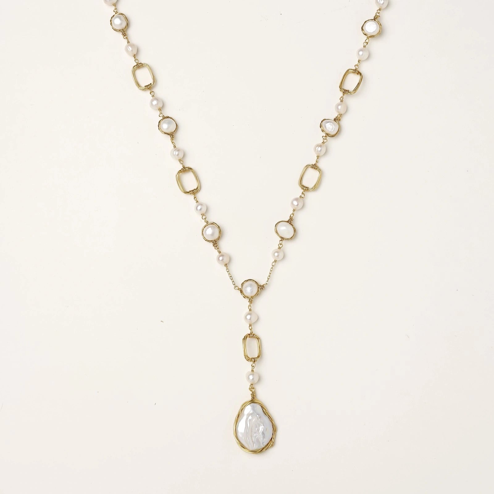 Long gold-plated necklace with alternating freshwater pearls and crystal bezels, featuring a large baroque pearl pendant