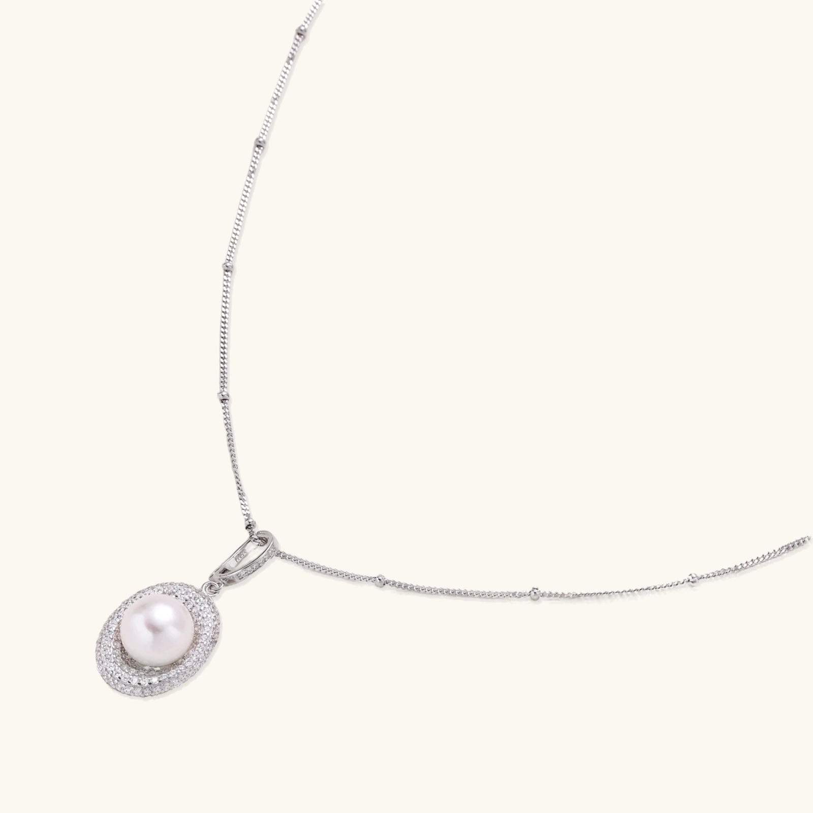 Oval sterling silver pendant with crystal halo surrounding a white freshwater pearl on delicate chain