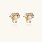 Gold-plated flower stud earrings with textured petals and centered freshwater pearl on beige background
