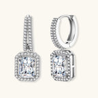 Sterling silver huggie hoops with emerald-cut moissanite drops featuring pavé-set crystals on white background.